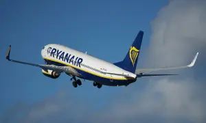 Samolot Ryanair wznoszący się na tle błękitnego nieba z chmurami.