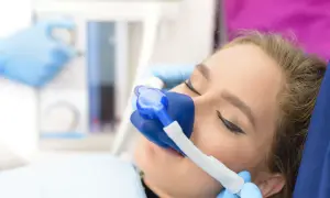 Kobieta z maską gazową na twarzy podczas zabiegu stomatologicznego.