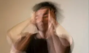 Rozmyta postać z rękami na głowie, symbolizująca stres i niepokój.