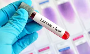 Ręka w niebieskiej rękawiczce trzyma probówkę z krwią do testu na mleczan.