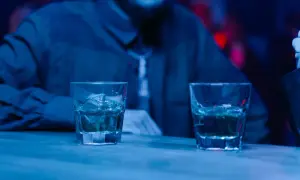Dwa drinki na barze, a obok siedzi osoba. Czy można pić alkohol po radioterapii? To pytanie nurtuje wielu pacjentów.