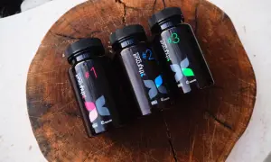 Trzy czarne butelki suplementu thyroset z numerami 1, 2 i 3, ułożone na drewnianej desce.