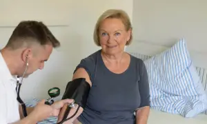 Lekarz mierzy ciśnienie starszej kobiecie. To ważny krok w wykrywaniu nadciśnienia i jego objawów.