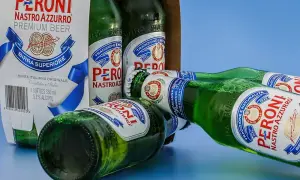 Butelki piwa Peroni Nastro Azzurro leżą obok kartonu. Czy można trzymać alkohol w plastiku? Te butelki są szklane.
