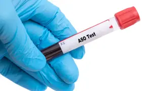 Ręka w niebieskiej rękawiczce trzyma probówkę z napisem "ASO Test".