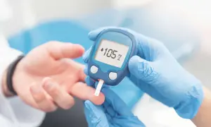 Osoba w niebieskich rękawiczkach wykonuje badanie glukozy, przykładając glukometr do palca pacjenta. Wynik 105 mg/dL.