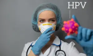 Lekarka w masce i czepku trzyma model wirusa HPV.