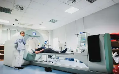 Pacjent leży na stole do badań, a technik przygotowuje się do wykonania scyntygrafii kości.