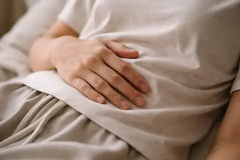 Dłoń na brzuchu, symbolizująca troskę o zdrowie i diagnostykę, np. test ureazowy.