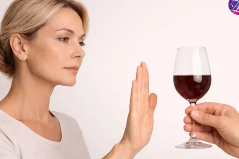 Kobieta odrzuca kieliszek czerwonego wina, sugerując, że po rezonansie można pić alkohol, ale ona woli odmówić.