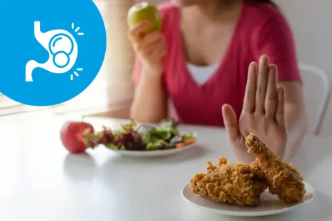 Symbol żołądka z bąbelkami i ręka odrzucająca smażonego kurczaka. Zdrowa dieta to klucz do tego, co na wzdęcia.