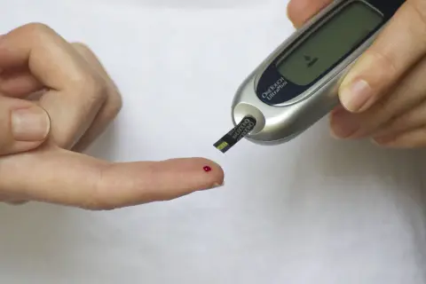 Pomiar glukozy glukometrem przed podaniem insuliny na czczo. Kropelka krwi na palcu czeka na analizę.