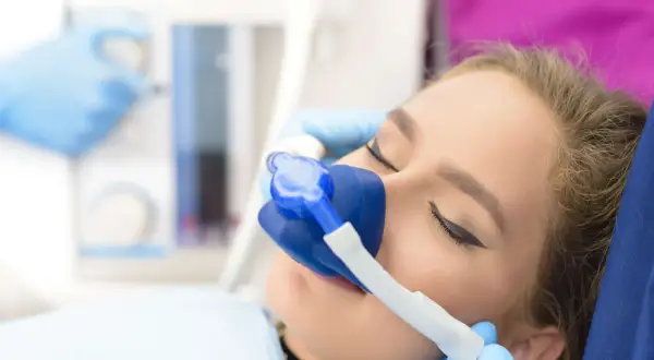 Kobieta z maską gazową na twarzy podczas zabiegu stomatologicznego.