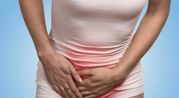 Kobieta trzymająca się za podbrzusze, z zaczerwienieniem w okolicy intymnej.