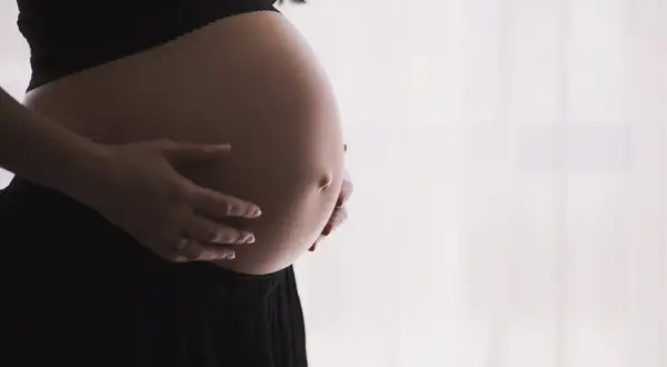Brzuch kobiety w ciąży, dłonie delikatnie go obejmują. Czas oczekiwania na dziecko, być może pierwsze skurcze przepowiadające.