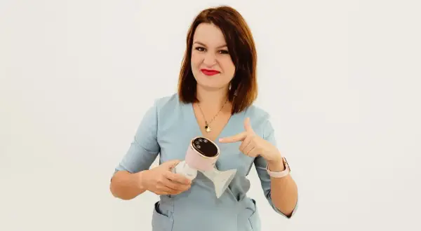 Kobieta w niebieskim fartuchu wskazuje na różowy laktator. To idealne rozwiązanie dla mam, które cenią sobie wygodę i nowoczesność, jak w przypadku Milanella Complex.