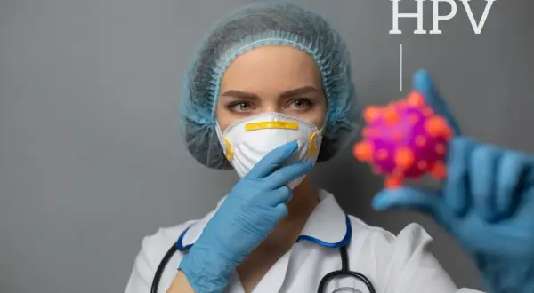 Lekarka w masce i czepku trzyma model wirusa HPV.