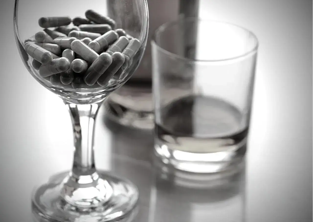 Kapsułki leku Nebilet 5 mg w kieliszku, obok szklanki z płynem. Pytanie: Nebilet 5 mg czy można pić alkohol?