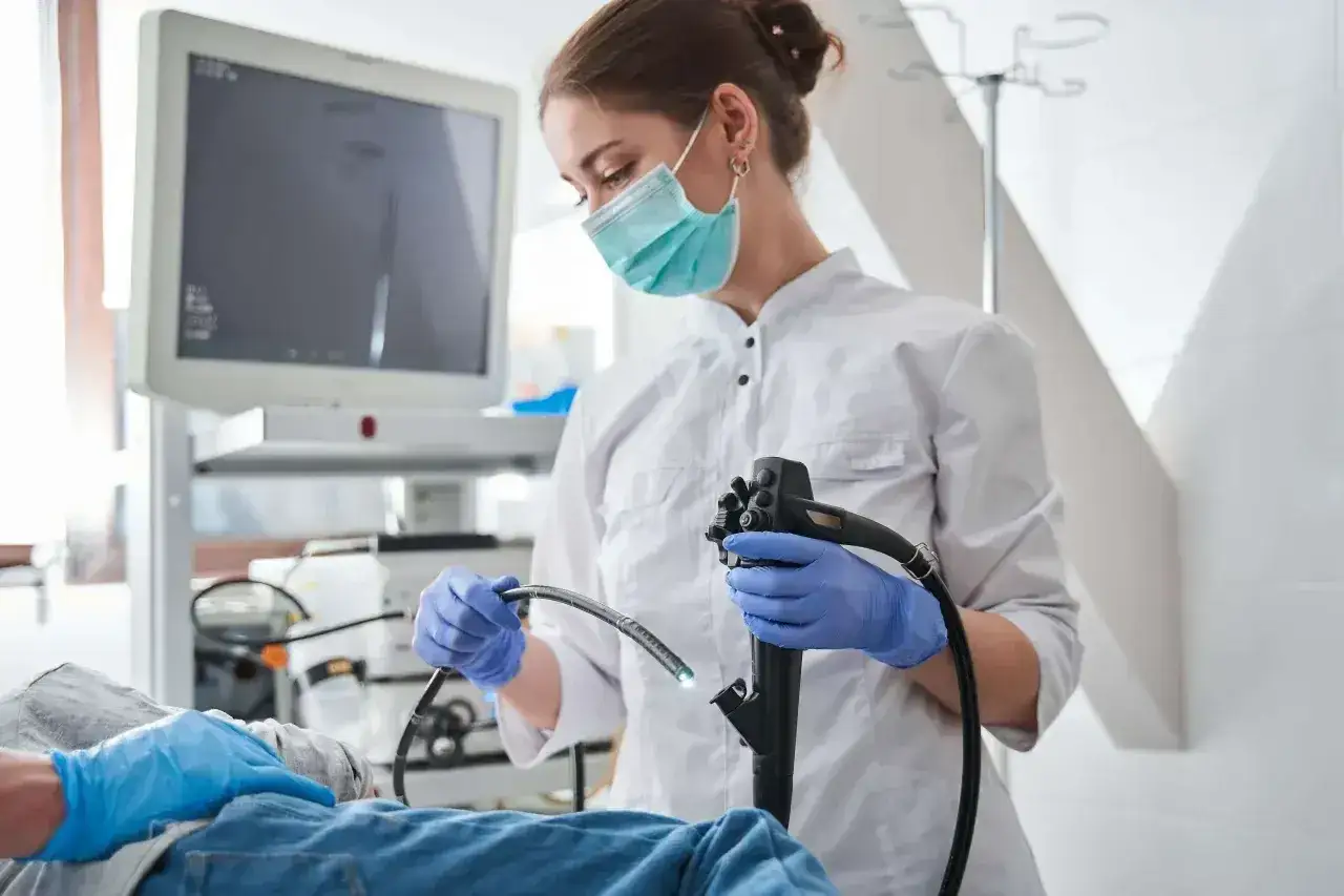 Lekarka w masce i rękawiczkach przygotowuje się do gastroskopii. Po zabiegu warto unikać alkoholu, by organizm mógł się zregenerować.