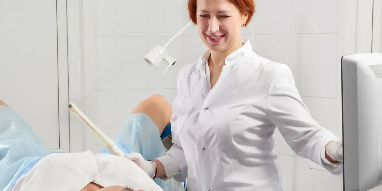 Lekarka bada pacjentkę, która leży na fotelu ginekologicznym. W gabinecie panuje sterylna atmosfera, a lekarz wykonuje badanie USG, które może pomóc zdiagnozować zapalenie pochwy.