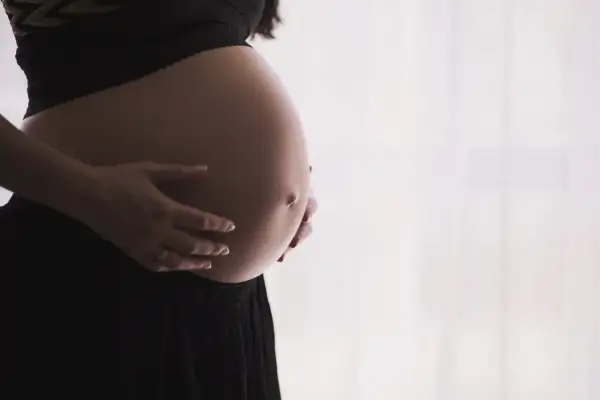 Brzuch kobiety w ciąży, dłonie delikatnie go obejmują. Czas oczekiwania na dziecko, być może pierwsze skurcze przepowiadające.