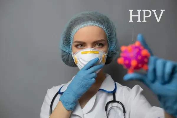 Lekarka w masce i czepku trzyma model wirusa HPV.
